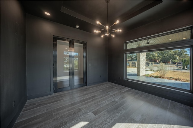 empty room featuring dark wood-style floors, baseboards, and an inviting chandelier