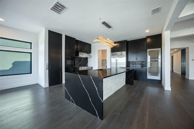 kitchen featuring dark wood-type flooring, dark countertops, stainless steel built in refrigerator, and visible vents