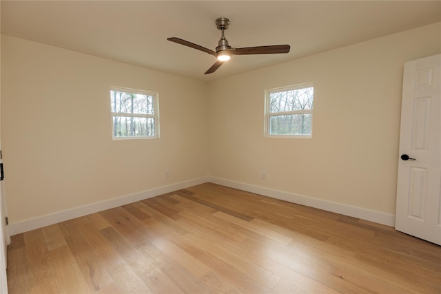 spare room featuring light wood finished floors, a ceiling fan, a wealth of natural light, and baseboards