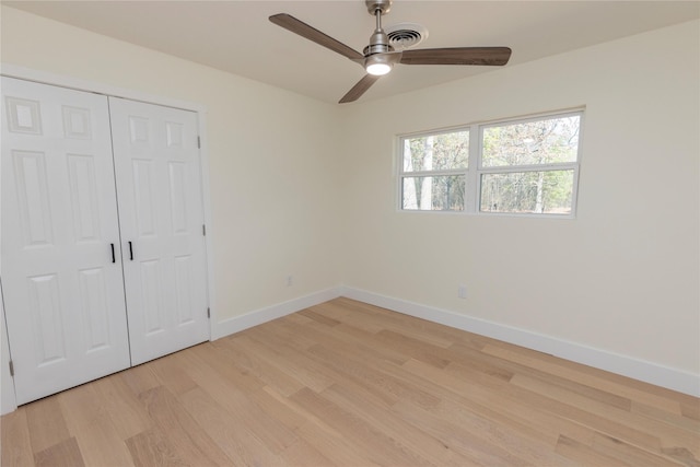 unfurnished bedroom featuring visible vents, baseboards, light wood-style flooring, ceiling fan, and a closet