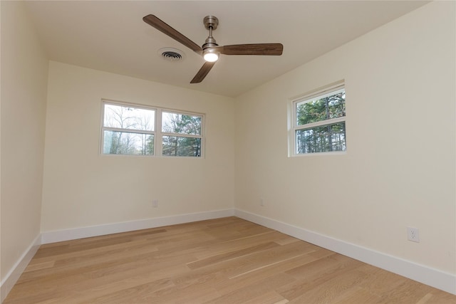 empty room featuring a ceiling fan, light wood-type flooring, visible vents, and baseboards