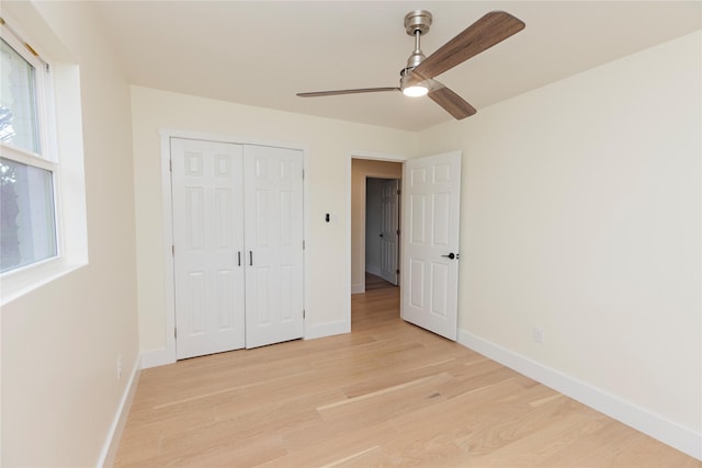 unfurnished bedroom featuring light wood finished floors, multiple windows, and baseboards