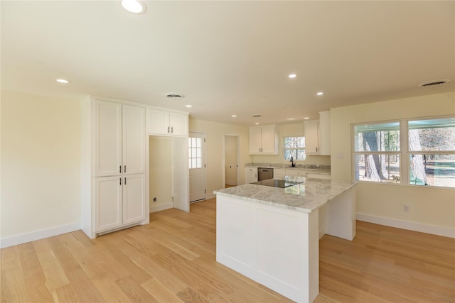 kitchen with light wood-style flooring, recessed lighting, a sink, visible vents, and white cabinetry