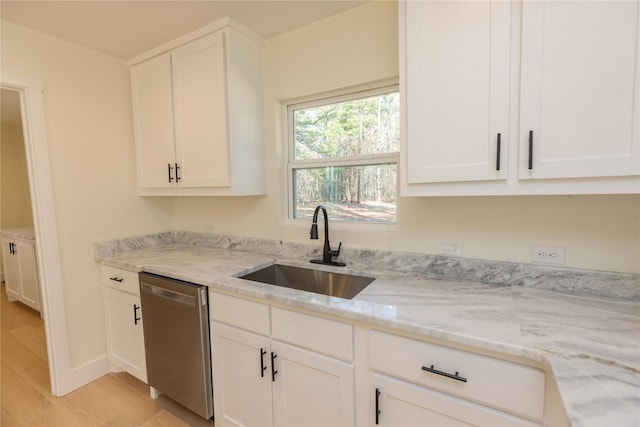 kitchen with dishwasher, light stone countertops, light wood-type flooring, white cabinetry, and a sink