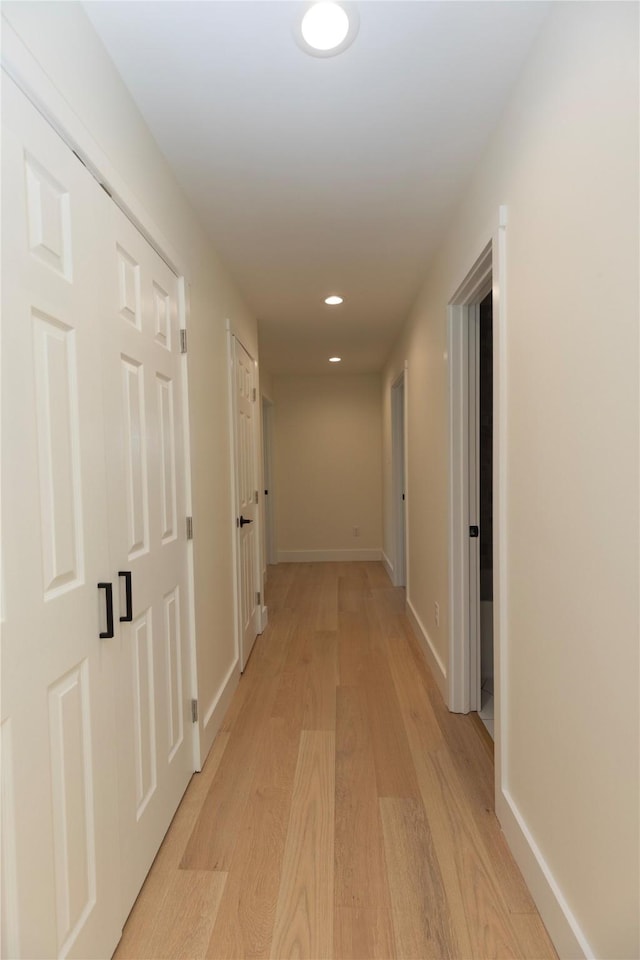 corridor featuring light wood-type flooring, baseboards, and recessed lighting