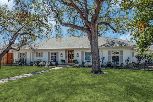 single story home featuring a shingled roof, a front yard, and brick siding