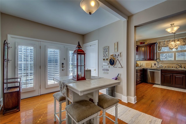 dining room with baseboards, light wood finished floors, and a notable chandelier