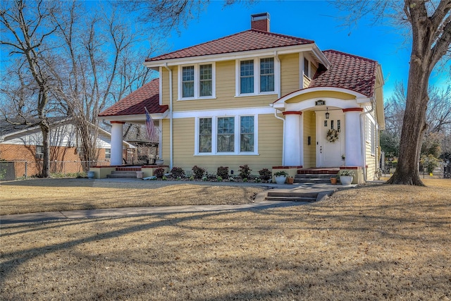 mediterranean / spanish-style home featuring a tile roof, fence, a chimney, and a front lawn