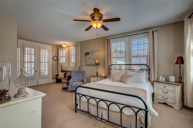 bedroom with access to exterior, light colored carpet, ceiling fan, and multiple windows