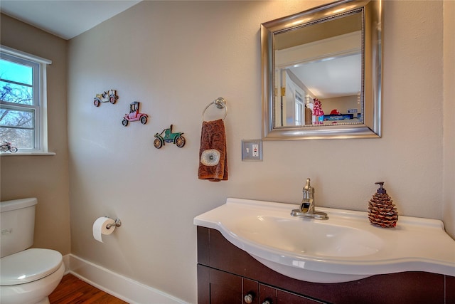 bathroom featuring toilet, baseboards, wood finished floors, and vanity