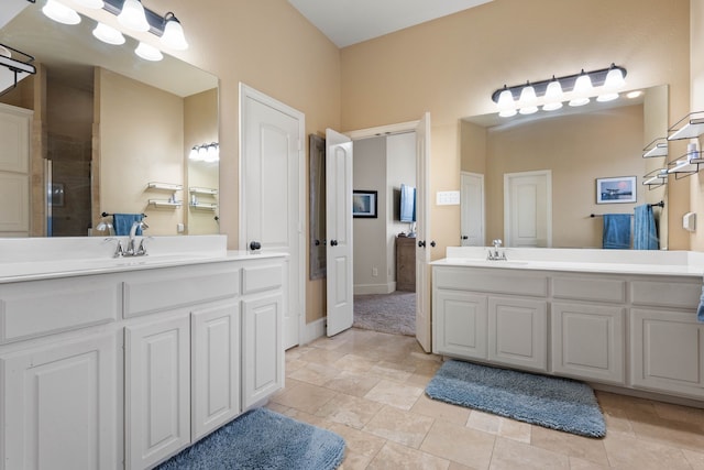 full bath with an enclosed shower, two vanities, a sink, and baseboards