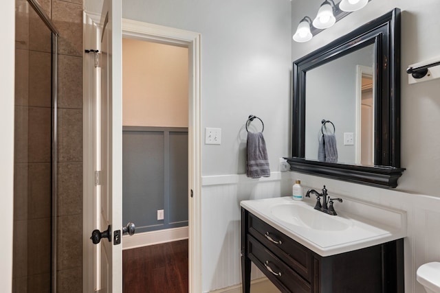 bathroom with a wainscoted wall, wood finished floors, and vanity