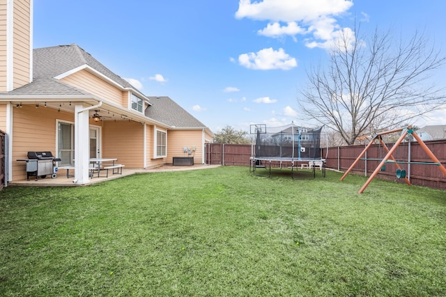 view of yard with a patio, a playground, a fenced backyard, a ceiling fan, and a trampoline