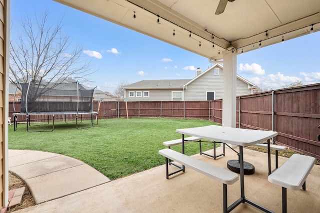 view of yard with a trampoline, a fenced backyard, a patio, and a ceiling fan