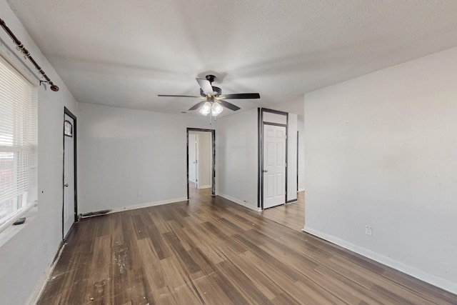 empty room with a ceiling fan, a textured ceiling, baseboards, and wood finished floors