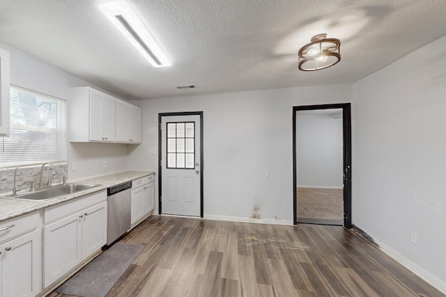 kitchen featuring dishwasher, wood finished floors, light countertops, white cabinetry, and a sink