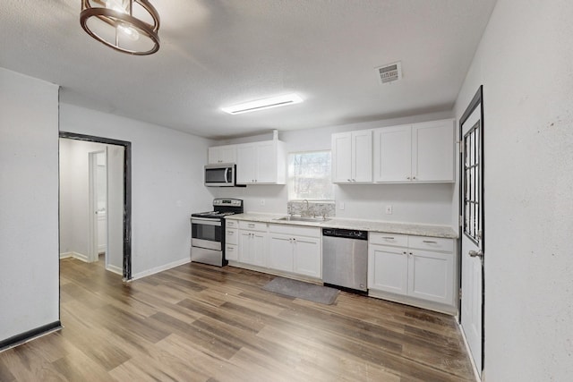 kitchen with white cabinetry, visible vents, appliances with stainless steel finishes, and light countertops