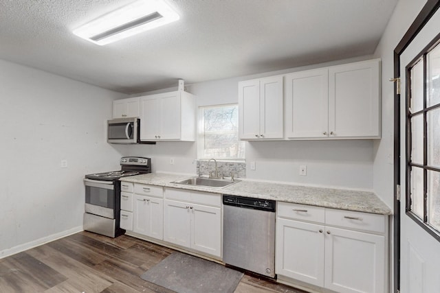 kitchen with a textured ceiling, dark wood-type flooring, a sink, white cabinets, and appliances with stainless steel finishes