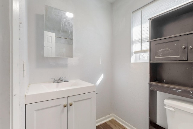 bathroom featuring wood finished floors, vanity, toilet, and baseboards