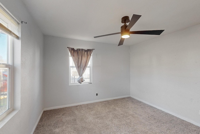 carpeted spare room featuring a ceiling fan and baseboards