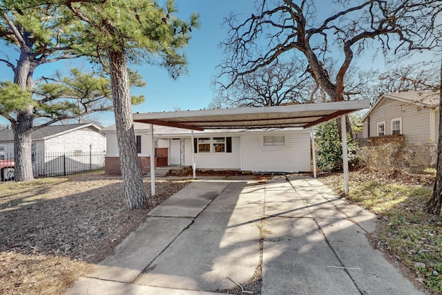 view of front of property featuring a carport, concrete driveway, brick siding, and fence