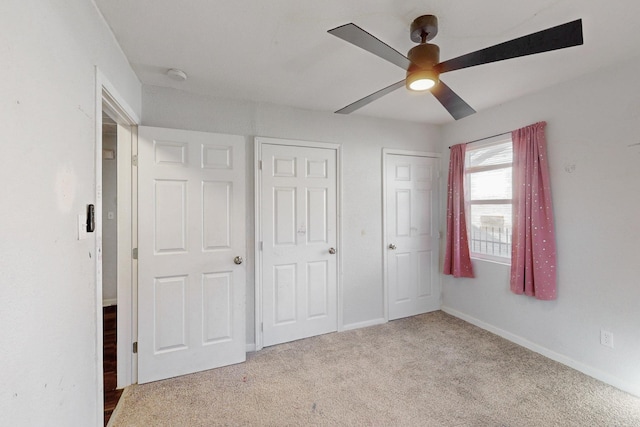 unfurnished bedroom with ceiling fan, carpet, and baseboards