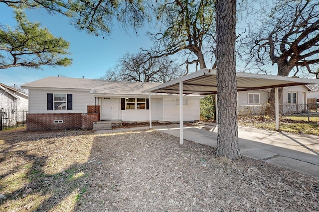 ranch-style home featuring a carport, brick siding, fence, and driveway