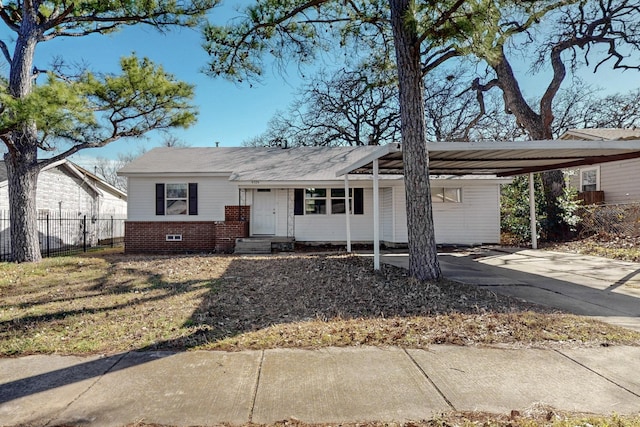 view of front of house featuring brick siding, crawl space, fence, a carport, and driveway