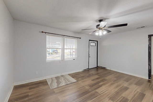 spare room featuring visible vents, a textured ceiling, baseboards, and wood finished floors