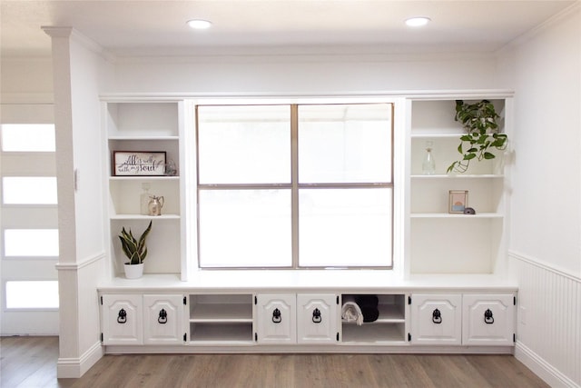 mudroom with a wainscoted wall, crown molding, light wood-type flooring, and built in features