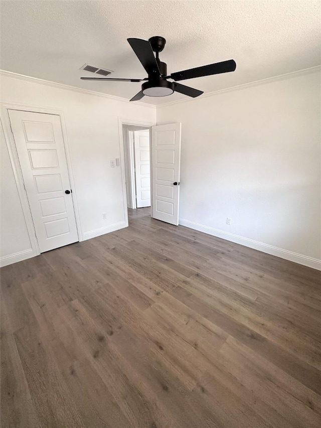 unfurnished bedroom featuring dark wood-style floors, baseboards, visible vents, and a textured ceiling