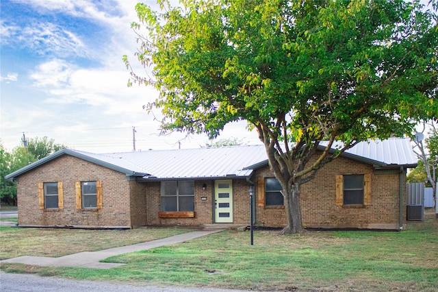 ranch-style home featuring brick siding, metal roof, and a front yard