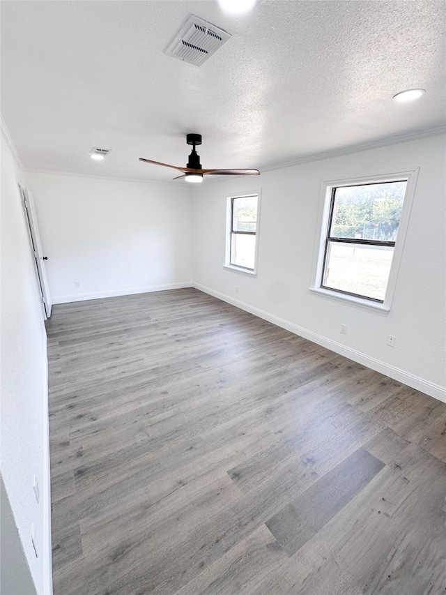 empty room with baseboards, a textured ceiling, visible vents, and wood finished floors