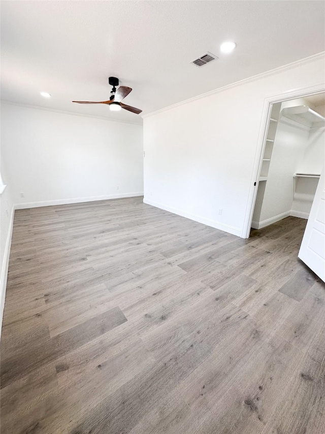 unfurnished room featuring crown molding, visible vents, a ceiling fan, wood finished floors, and baseboards