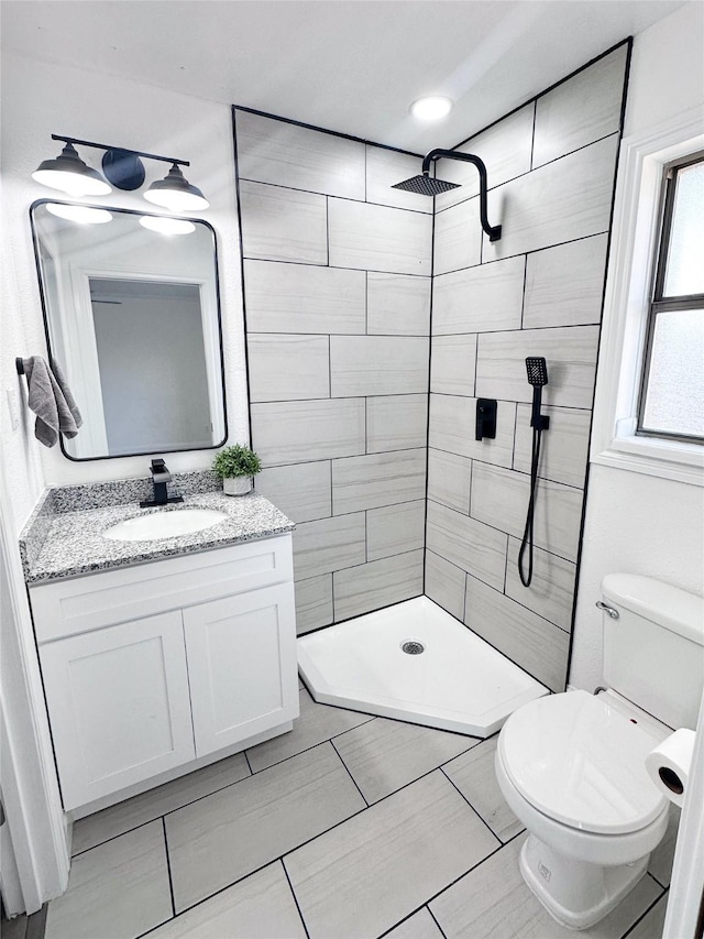 bathroom featuring tiled shower, vanity, and toilet