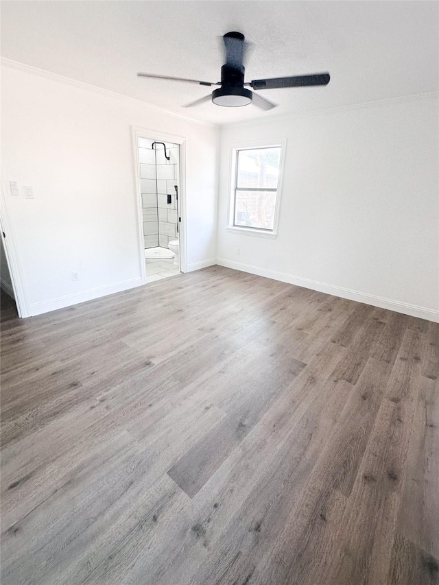 empty room featuring a ceiling fan, baseboards, and wood finished floors