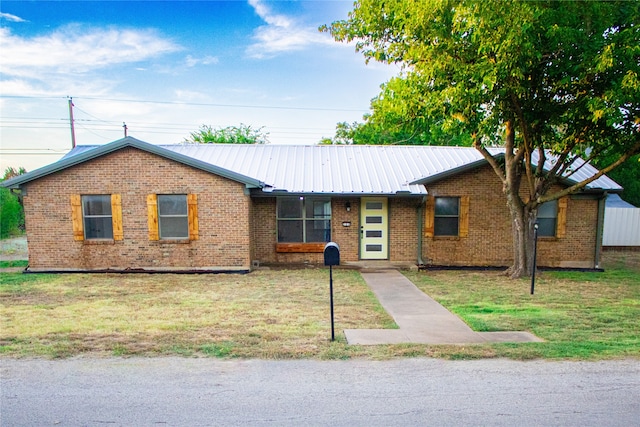 ranch-style house with brick siding, metal roof, and a front lawn