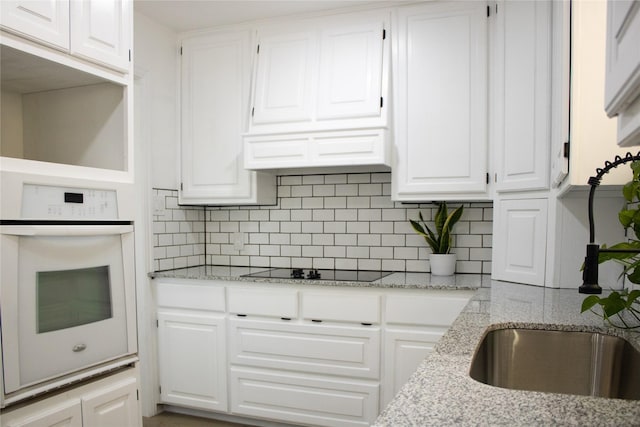 kitchen featuring white cabinetry, oven, and black electric cooktop