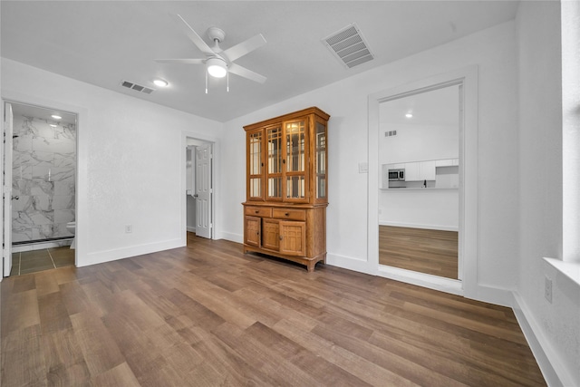 spare room with ceiling fan, wood finished floors, visible vents, and baseboards