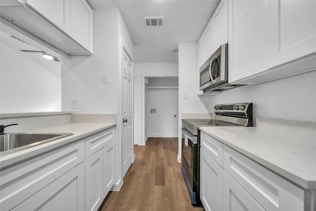 kitchen featuring stainless steel appliances, a sink, visible vents, white cabinetry, and light countertops