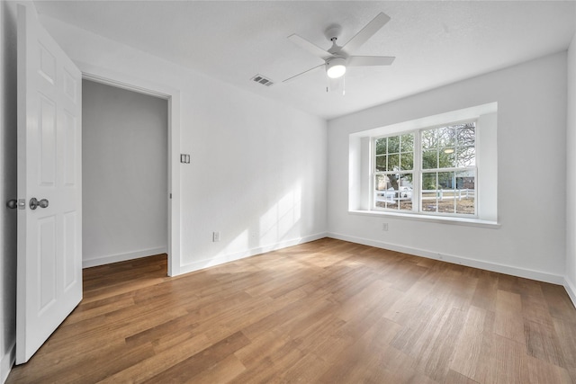 empty room featuring baseboards, visible vents, ceiling fan, and light wood finished floors