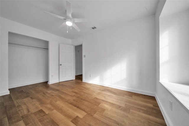 unfurnished bedroom featuring a closet, wood finished floors, visible vents, and baseboards