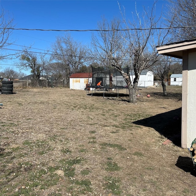 view of yard featuring an outbuilding, a storage unit, and a trampoline