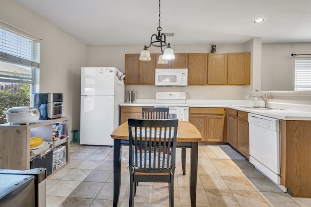 kitchen with decorative light fixtures, light countertops, visible vents, a sink, and white appliances