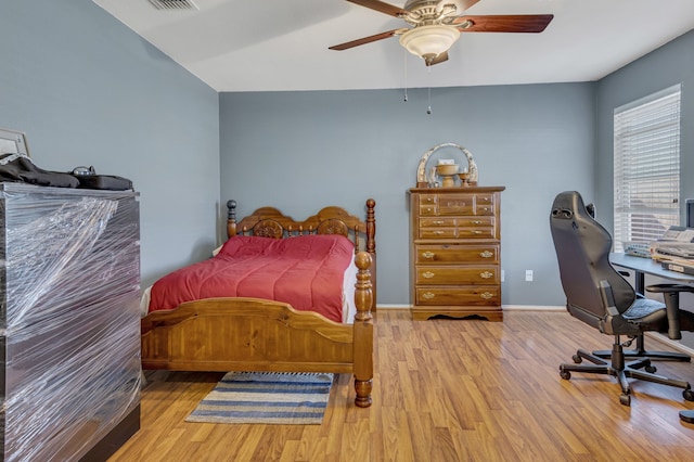 bedroom with ceiling fan, visible vents, baseboards, and wood finished floors