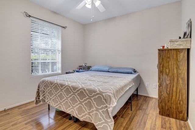 bedroom featuring ceiling fan, baseboards, and wood finished floors