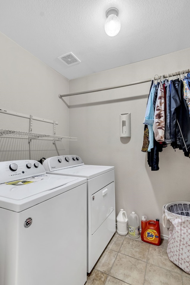 laundry area featuring a textured ceiling, light tile patterned flooring, laundry area, separate washer and dryer, and visible vents