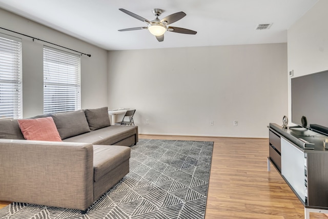 living area with light wood-style floors, visible vents, baseboards, and a ceiling fan