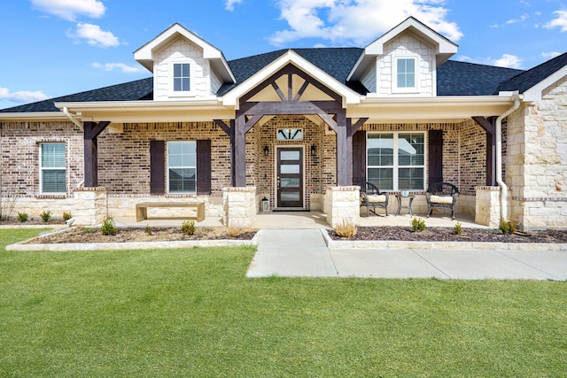 craftsman-style home with brick siding, a porch, a shingled roof, and a front lawn