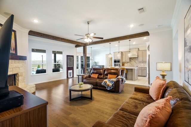 living area featuring visible vents, recessed lighting, a stone fireplace, crown molding, and light wood finished floors